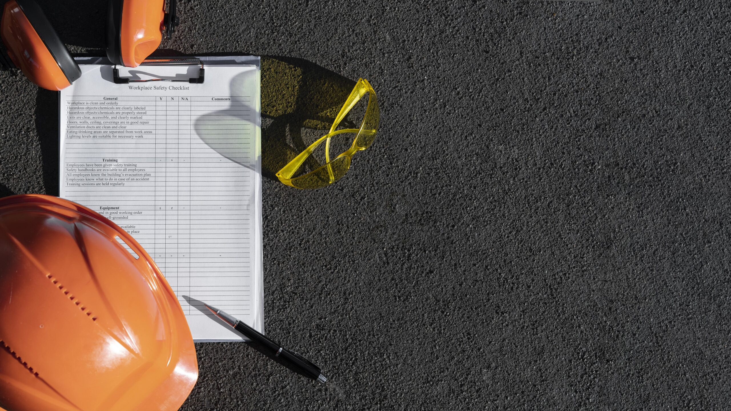 disposizione-piana-con-dotazioni-di-sicurezza Dispositivi di protezione individuale e checklist di sicurezza sul lavoro su superficie industriale, simbolo della prevenzione e della formazione efficace oltre la semplice documentazione.